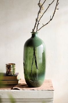 a green vase sitting on top of a table next to a stack of books