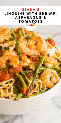 pasta with shrimp, asparagus and tomatoes in a white bowl on a marble table