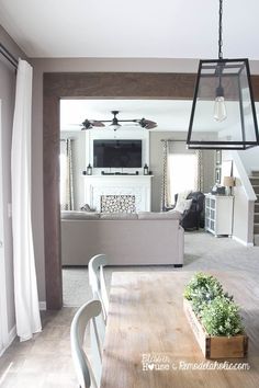 a living room and dining room with wood beam beams in the ceiling, white curtains on the windows