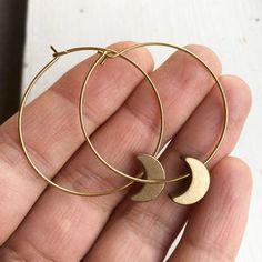 Crescent Moon Hoop EarringsThese light weight solid brass hoop earrings are the perfect accessory to finish an ensemble. Their warm golden hue catches the light and gives a little sparkle to your day.Also available in silver plated with stainless steel hoops. ➳ ITEM DETAILS:Hoop width: 1.25 inchesAll earring parts are solid brass✈ + ✉ SHIPPING / POLICIES:This listing is for one pair of earrings and they ships from Vancouver, Canada.Please see my shop policies for more details:https://www.etsy.co Gold Crescent Hoop Earrings In Brass, Hoop Earrings With Moon Charm, Gold Crescent Earrings With Moon Phase Detail, Gold Crescent Hoop Earrings With Ear Wire, Metal Moon-shaped Hoop Earrings, Gold Moon Shaped Metal Hoop Earrings, Minimalist Crescent Hoop Earrings, Nickel Free, Gold Moon-shaped Metal Hoop Earrings, Minimalist Crescent Hoop Earrings With Moon Charm