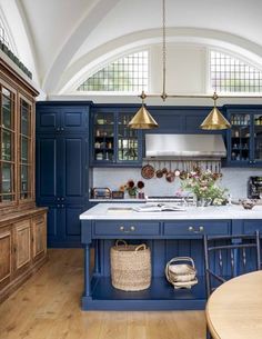 a large kitchen with blue cabinets and wooden floors, along with an island in the center