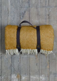 a yellow and black blanket sitting on top of a wooden floor next to a bag