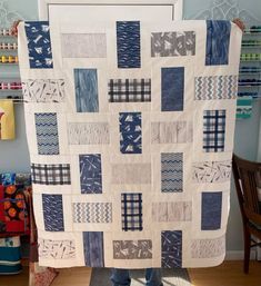 a person standing in front of a blue and white quilt