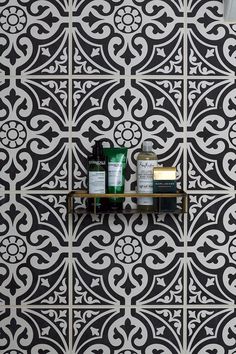 a shelf with some items on it in front of a wallpapered background that has black and white designs