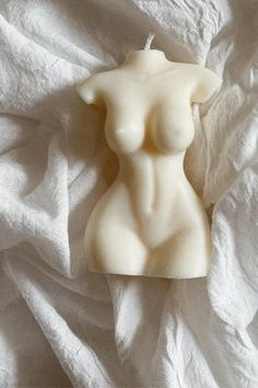 a candle shaped like a naked woman on a white sheet