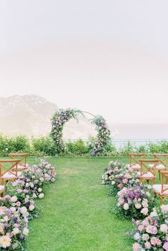 an outdoor ceremony set up with chairs and flowers on the grass, overlooking the ocean