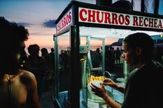 a man standing in front of a kiosk filled with bananas at night time