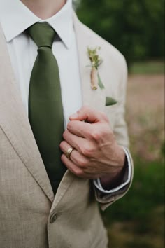 a close up of a person wearing a suit with a tie and boutonniere