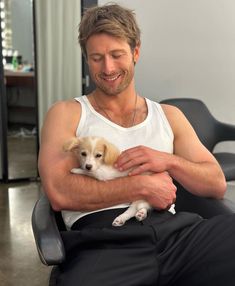 a man sitting in a chair holding a small dog