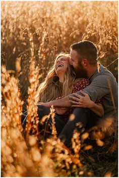 a couple cuddles in the tall grass during their engagement photo session at sunset