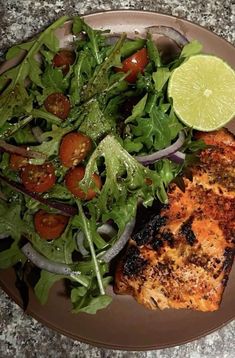 a plate filled with fish and salad on top of a table