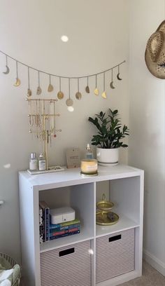 a white shelf with baskets and other items on it in a room that is decorated with lights