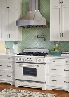 a stove top oven sitting inside of a kitchen next to white cupboards and drawers