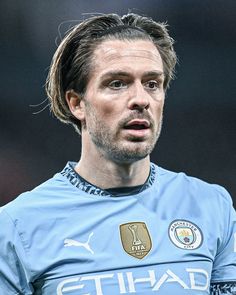 a close up of a soccer player wearing a blue uniform and looking off to the side