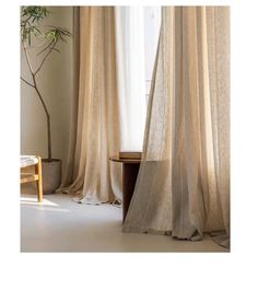 an open window with curtains and a table in front of it, next to a potted plant