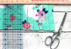 a pair of scissors next to a piece of fabric with flowers on it and a ruler