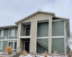 an apartment building with snow on the ground and stairs leading up to the second floor