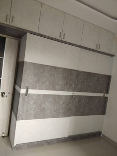 an empty room with white cabinets and gray marbled panels on the wall, in front of a doorway