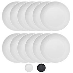 six white plates with black and white circles on the side, one is empty in front of