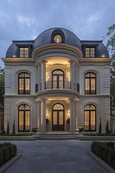 a large white house with lots of windows and lights on it's front entrance