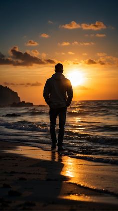 a man standing on top of a sandy beach next to the ocean at sunset or dawn