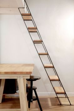 a wooden table with stools and a stair case in the corner next to it