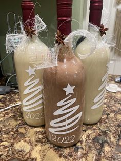 three bottles with christmas decorations on them sitting on a counter