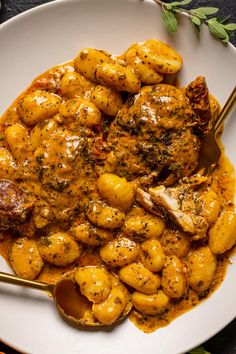 a white plate topped with chicken and gnocchini covered in gravy