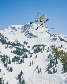 a man flying through the air while riding skis on top of a snow covered mountain