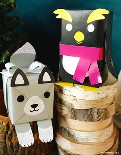 two paper animals sitting on top of each other next to some wood logs and a potted plant