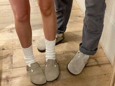 two people standing next to each other wearing slippers on the floor in front of a door