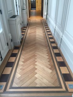 an empty hallway with wood floors and white walls