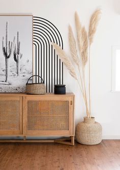 a wooden cabinet sitting on top of a hard wood floor next to a plant in a vase