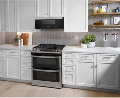 a kitchen with white cabinets and an oven in the center is shown, along with shelves that hold utensils