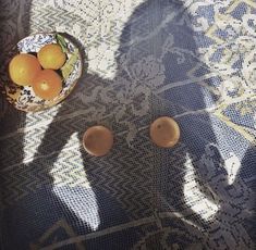 two oranges in a bowl sitting on a table next to another bowl with three oranges