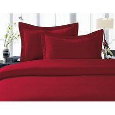 a bed with red sheets and pillows in a room