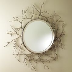 a mirror mounted to the side of a wall next to a tree branch decoration on a wall