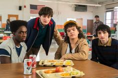 four young men sitting at a table with plates of food