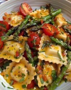 a white plate topped with pasta and veggies covered in cheese sauce on top of a table