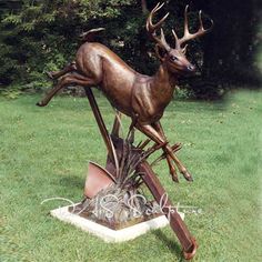 a bronze statue of a deer jumping over a pile of junk in the middle of a field