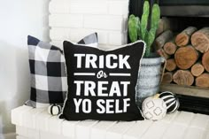 a black and white pillow sitting on top of a fire place next to a pile of logs