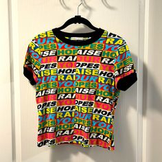 The “Raise Your Hopes” T-Shirt By Trendy And Chic Nyc Cult Brand Alice + Olivia. Euc. Beautiful Colors Throughout This Graphic Print. Features Black Ribbed Crew Neck And Short Sleeve Openings. No Visible Flaws. Size Small. Fits Like An Xsmall. A Terrific Statement Piece! Proud Posh Ambassador Ii All Items From My Smoke Free Home. All Designer Items Are Authentic. Fast Shipper. Thank You For Visiting My Closet! Happy Poshing! Multicolor Short Sleeve Tops With Logo Print, Multicolor Logo Print Tops For Summer, Multicolor Logo Print Short Sleeve Tops, Graphic Tee With Letter Print In Multicolor, Multicolor Graphic Tee With Logo Print, Multicolor Rainbow Print Short Sleeve T-shirt, Pride Multicolor Graphic Print T-shirt, Playful Multicolor Rainbow Print T-shirt, Designer Items