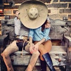 a woman sitting on top of a wooden bench next to a man in cowboy boots