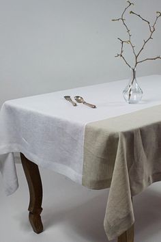 a table with a white cloth on it and a vase filled with silverware next to it