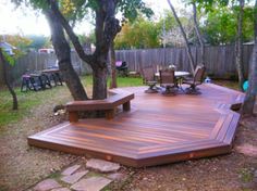 a wooden deck surrounded by trees and chairs