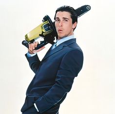 a man in a suit and tie holding a hair dryer on top of his head