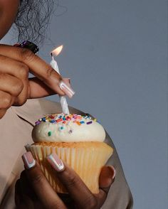 a woman lighting a candle on top of a cupcake