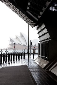 an empty walkway next to the water with a large building in the backgroud