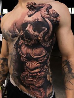 a man with a tattoo on his chest and head is holding a snake in the other hand