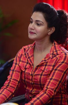 a woman sitting at a table with a laptop computer in her hand and looking off to the side